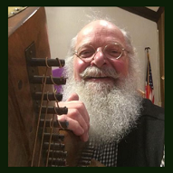 Smiling man with white beard holds a harp